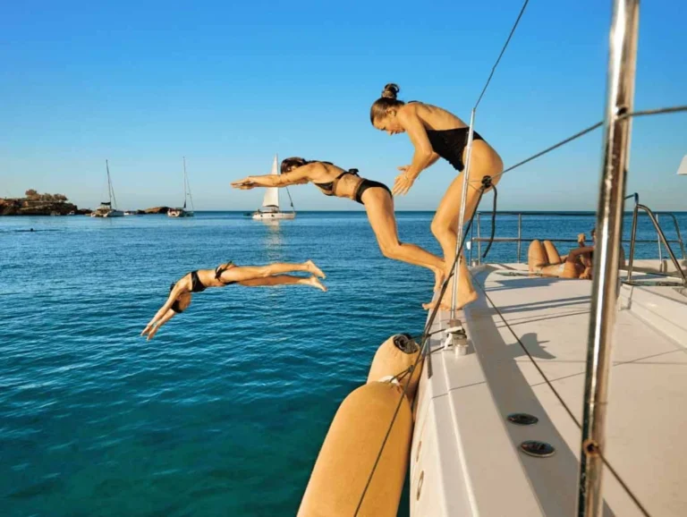 women diving into the sea from the board of a catamaran