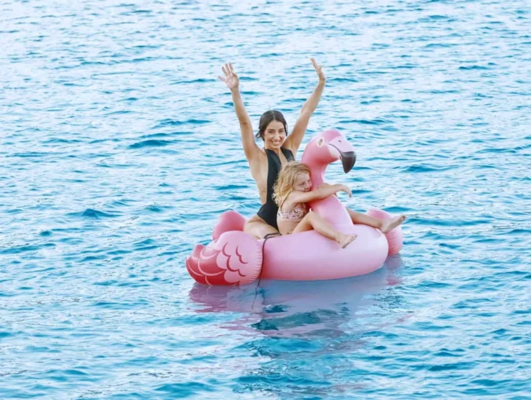 mother and daughter on a pink inflatable flamingo in the sea